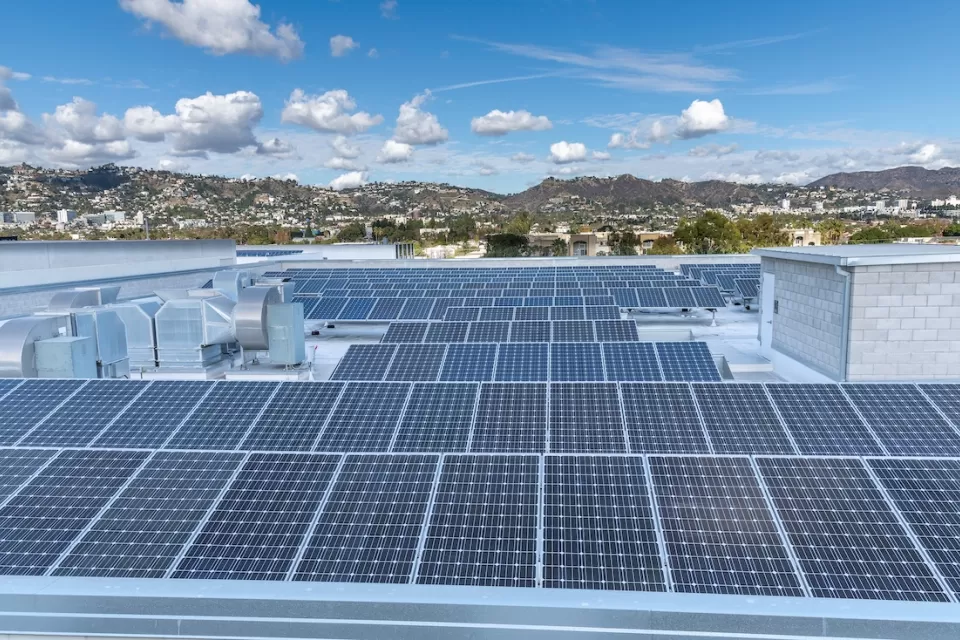 Large roof with solar panels and Los Angeles hills in background.